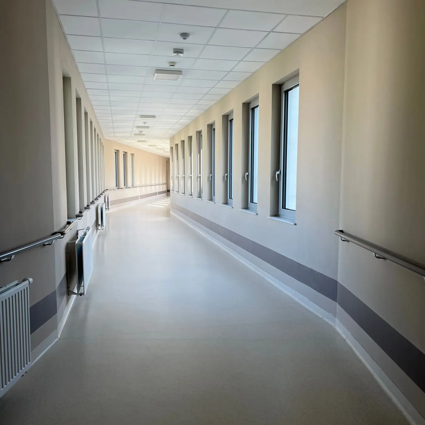 Couloir de structure de soins clair, éclairé par de larges fenêtres