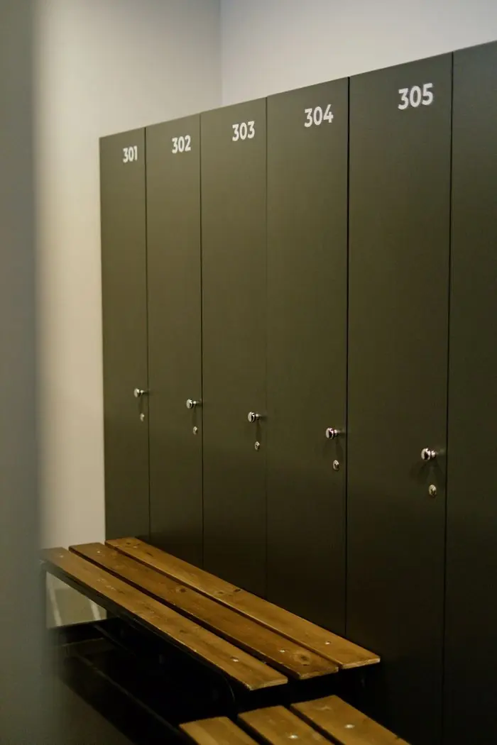 Vestiaire aux rangées d’armoires métalliques et bancs, sans occupant