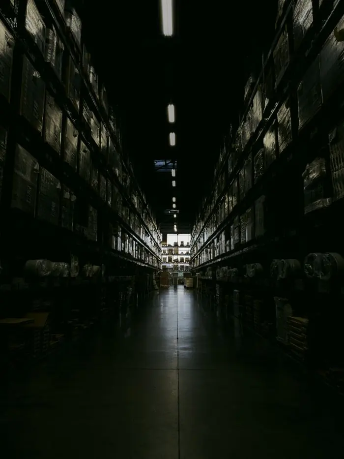 Allée d’entrepôt en faible éclairage, racks de stockage de grande hauteur