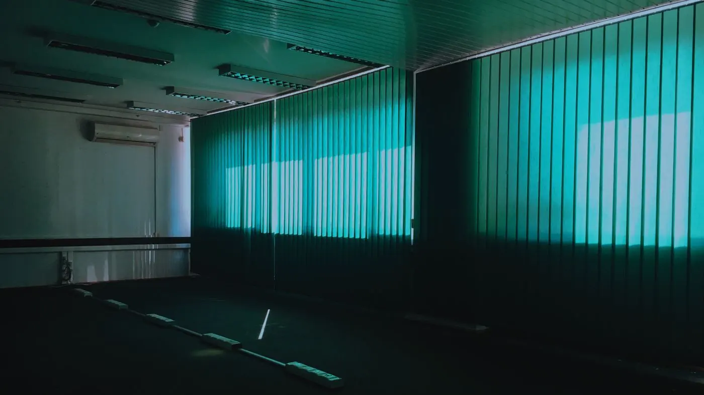 Plateau de bureaux vide en faible lumière, postes de travail alignés